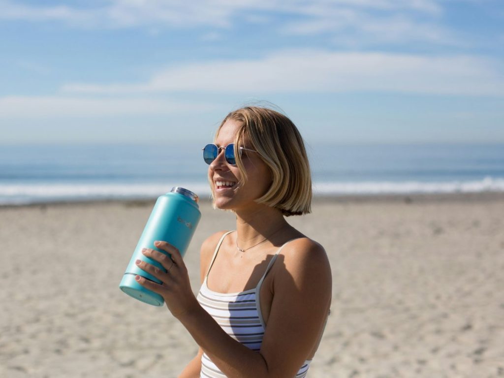 girl with smart water bottle on beach